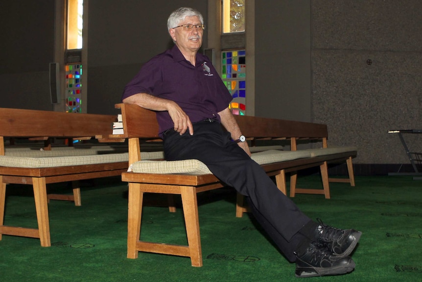 Bishop Gary Nelson sits on a pew in a church.