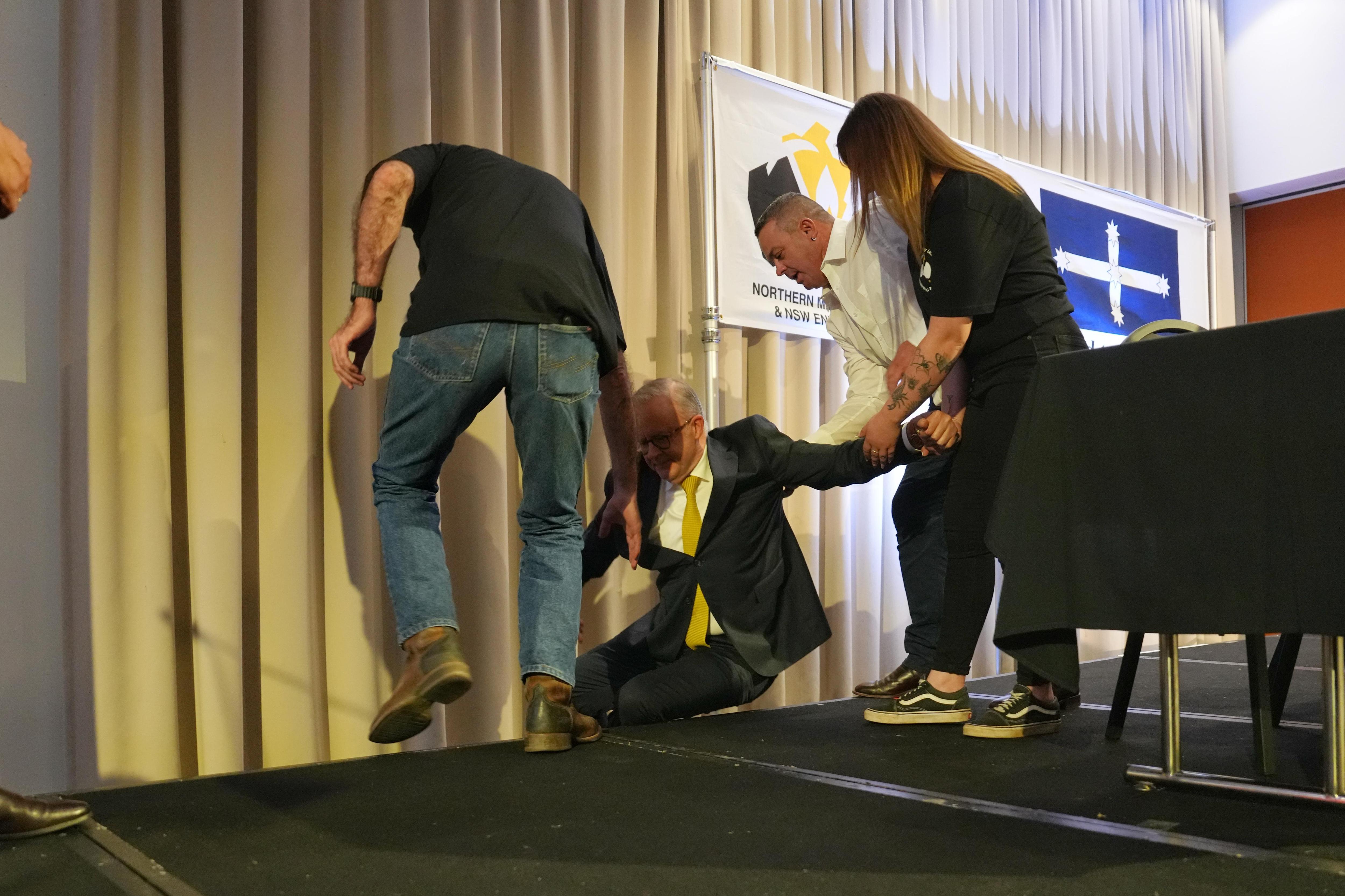 Anthony Albanese holding on to several people as he takes a tumble.