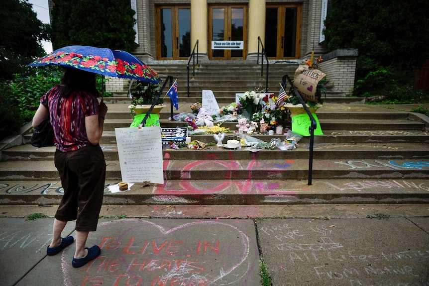 A woman views a memorial for Justine Damond on the steps of the Lake Harriet Spiritual Community church in south Minneapolis.