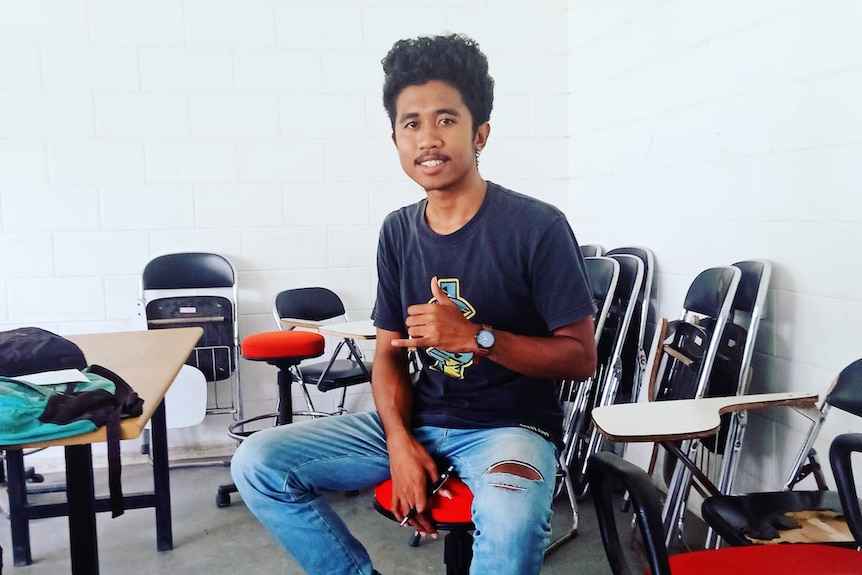 22-year-old Benjamin sitting in a classroom with a thumbs up