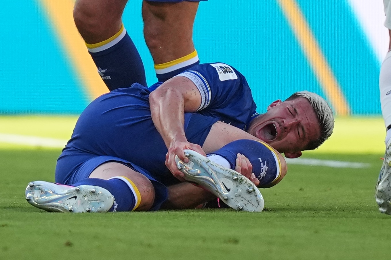 Tarik Muharemović screams, holding his foot while laying on the ground.