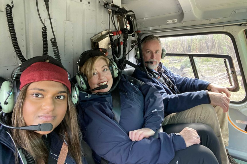 three people in a helicopter seat