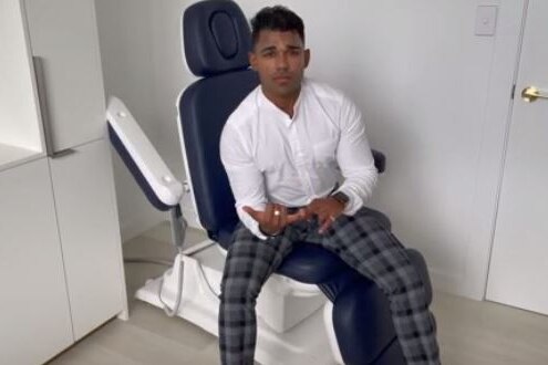 A man sitting on a medical chair speaking to the camera.
