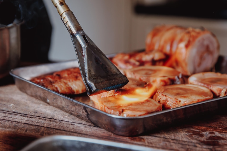 Wild Boar belly in a try being flamed by a chef