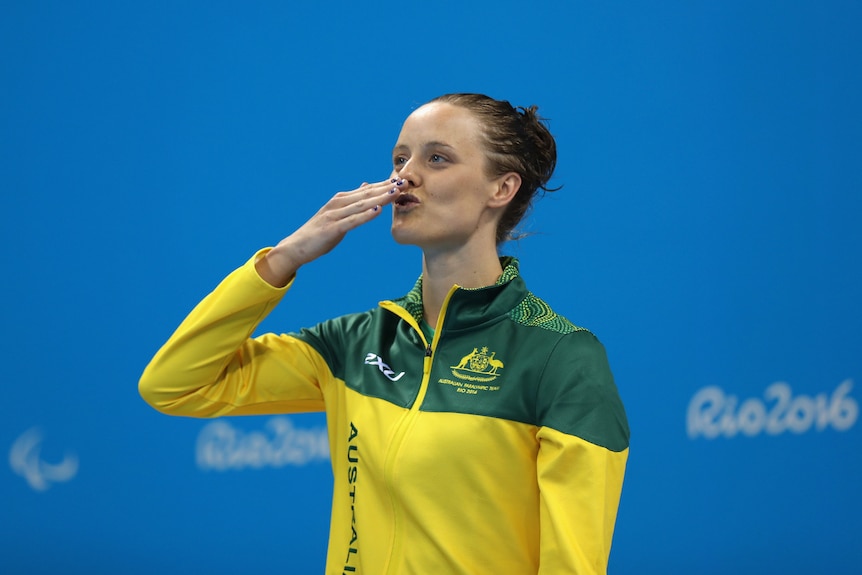 An Australian Paralympic swimmer blows a kiss to the crowd after winning a medal. 
