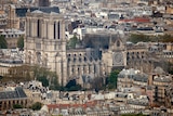 The Notre Dame Cathedral is seen from a distance, showing massive fire damage