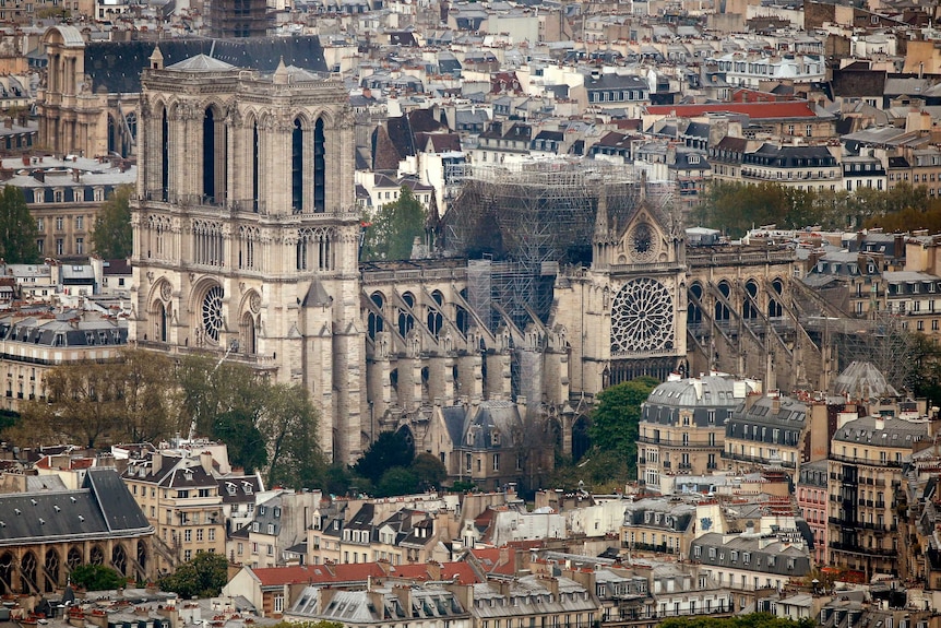 The Notre Dame Cathedral is seen from a distance, showing massive fire damage