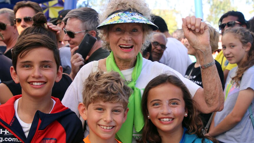 Gillian raises her arm, three grandchildren smile in front of her.