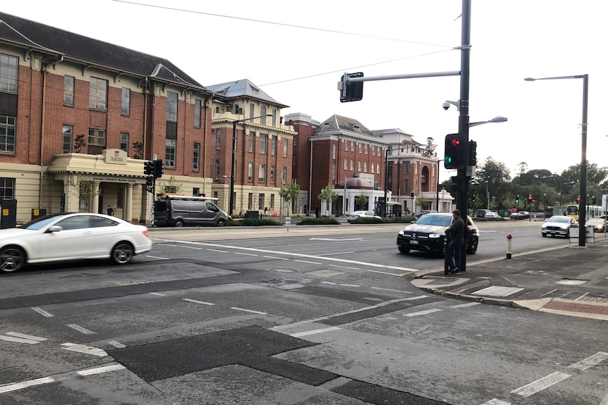 A intersection with cars, tram wires and old buildings