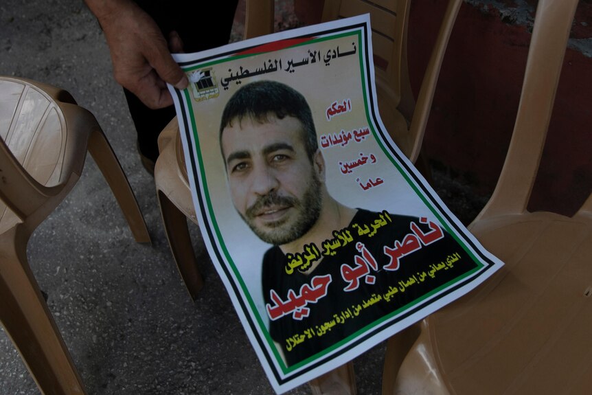 A poster of a Palestinian man surrounded by Arabic writing.