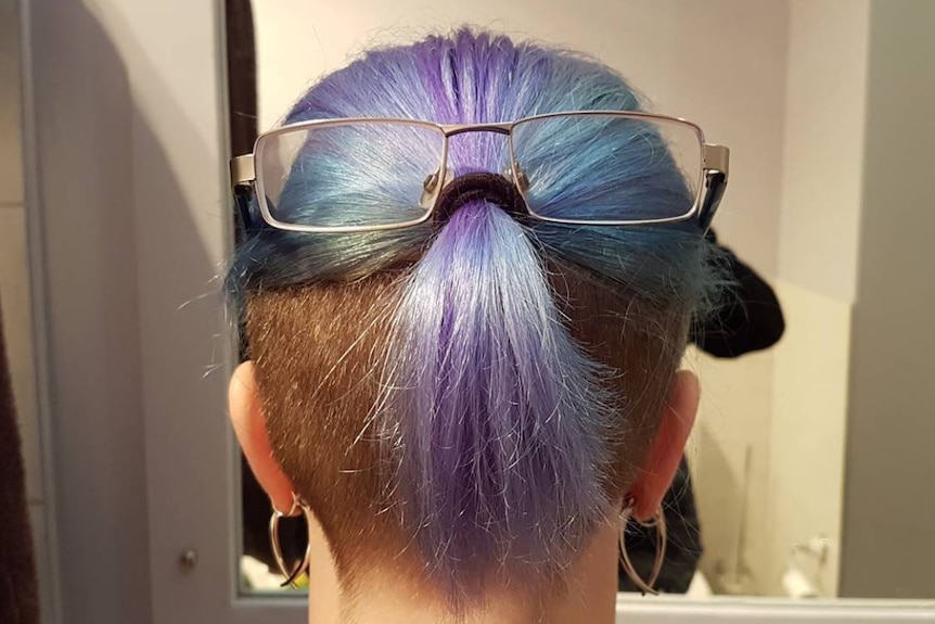 Pastel coloured hair in a pony tail with a pair of glasses placed on the pony tail