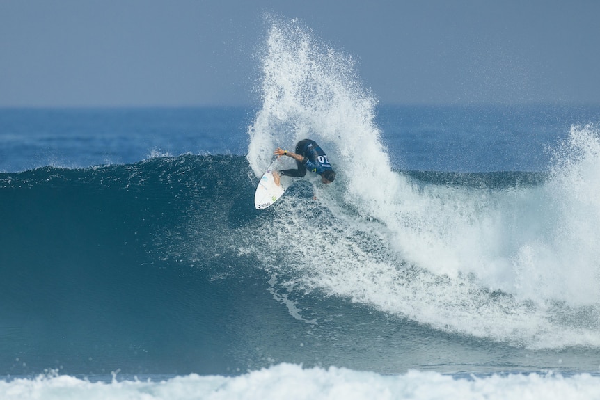 A man on a surfboard catching a wave at the beach