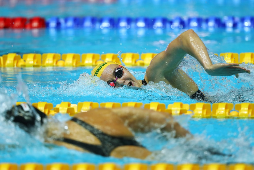 Katie Ledecky and Ariarne Titmus look at each other as they swim