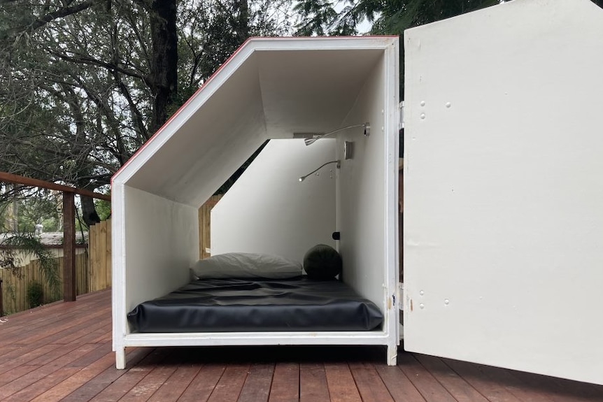 An accommodation capsule that contains a mattress and a phone charger.