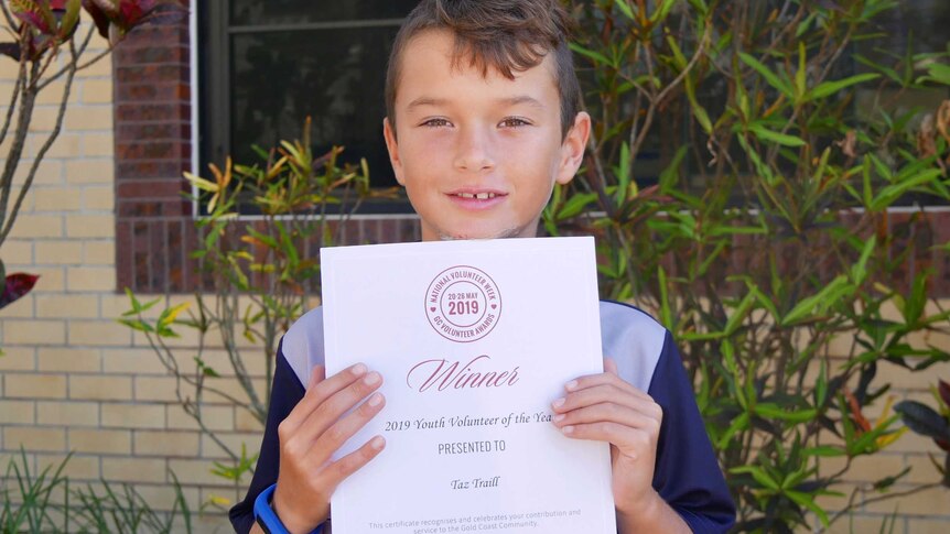 Photo of eight- year-old Taz Traill with his certificate for winning Gold Coast Youth Volunteer of the Year.