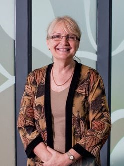 A woman with spectacles smiles at the camera