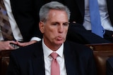 Close up of a man in a suit biting his top lip.  