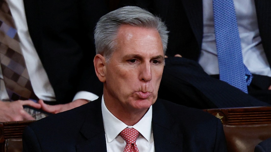 Close up of a man in a suit biting his top lip.  