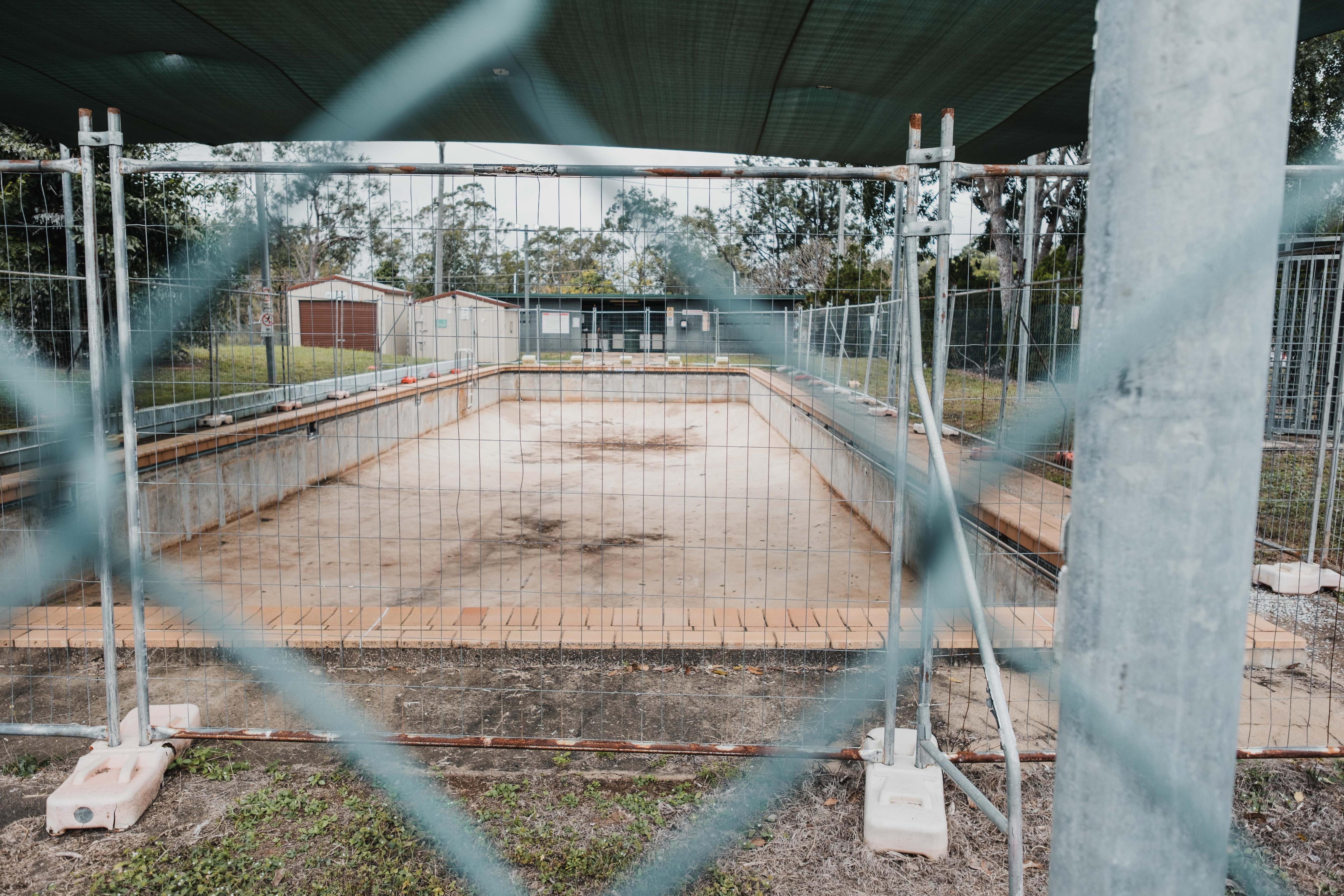 Uma piscina vazia atrás de uma cerca de arame farpado