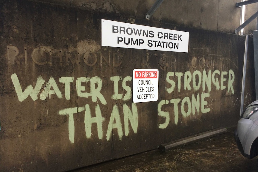 "Water is stronger than stone" painted on the cement wall of the Browns Creek Pump Station in Lismore.