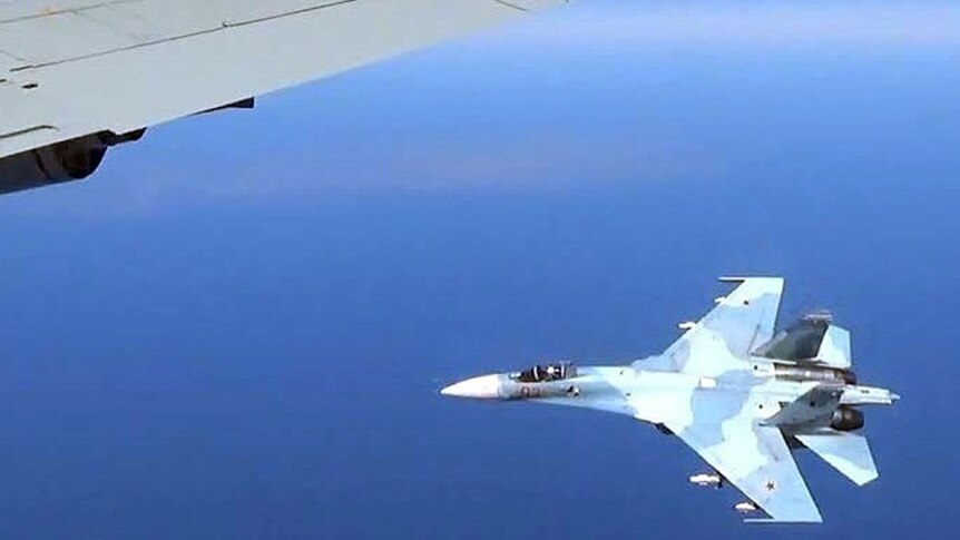 Fighter jet in Russian markings flies under the wing of a US Air Force plane