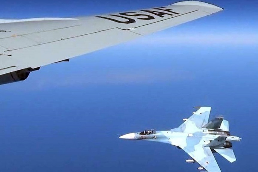 Fighter jet in Russian markings flies under the wing of a US Air Force plane