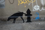 People walk by street art graffiti in New York by Banksy