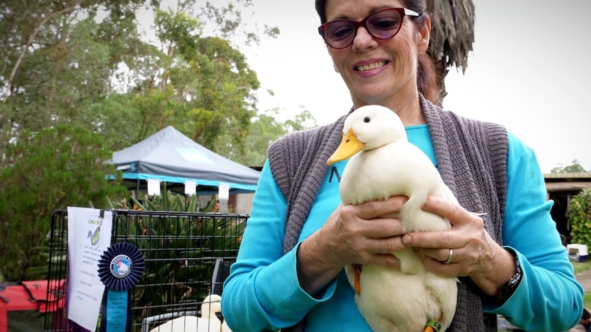 A woman holds a small white duck