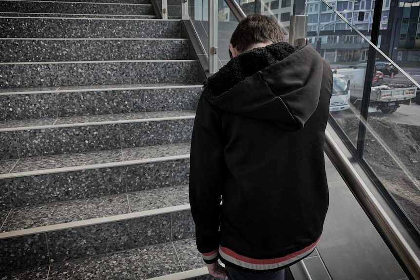 An unidentifiable shot of a teenage boy walking up stairs