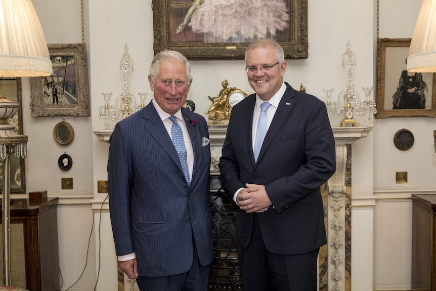 Prince Charles poses with Prime Minister Scott Morrison in a room with paintings of ballet dancers and lampshades