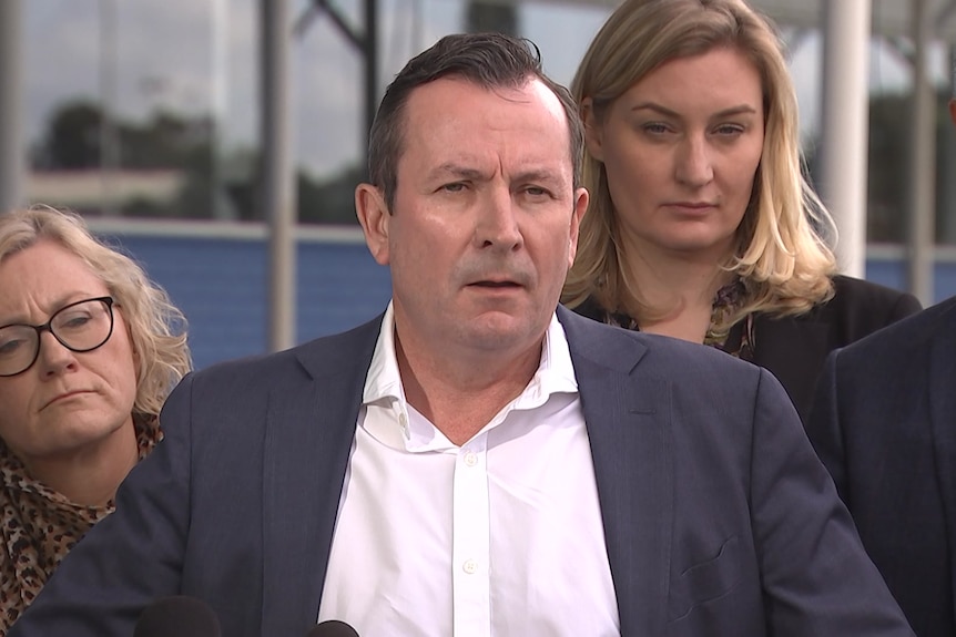 Man in grey suit, white shirt, brown hair speaks