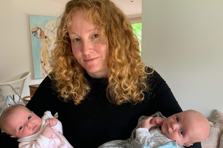 Elizabeth Medland cradles her newborn twins in her arms.