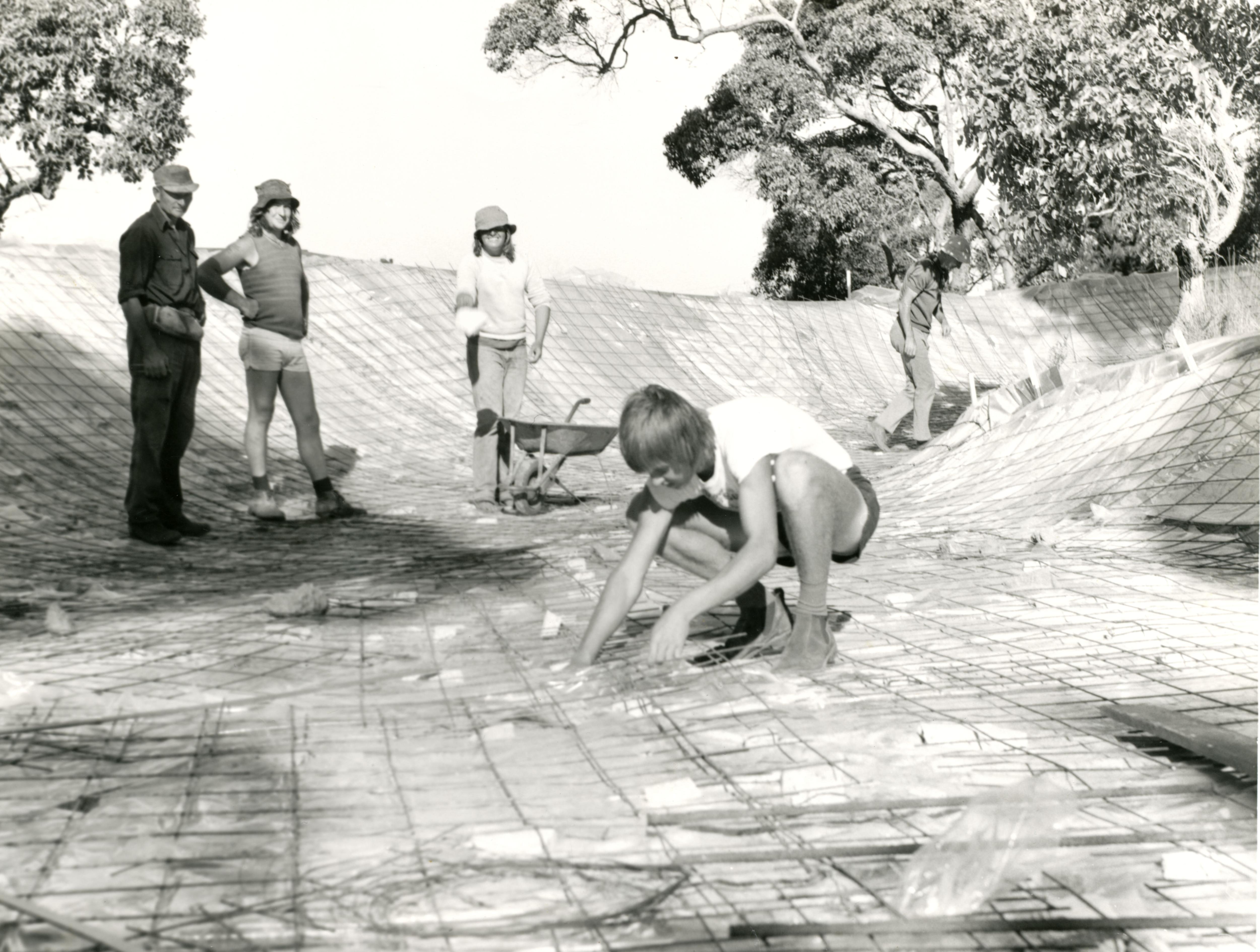 Una fotografía en blanco y negro de personas asegurando redes para verter hormigón. 