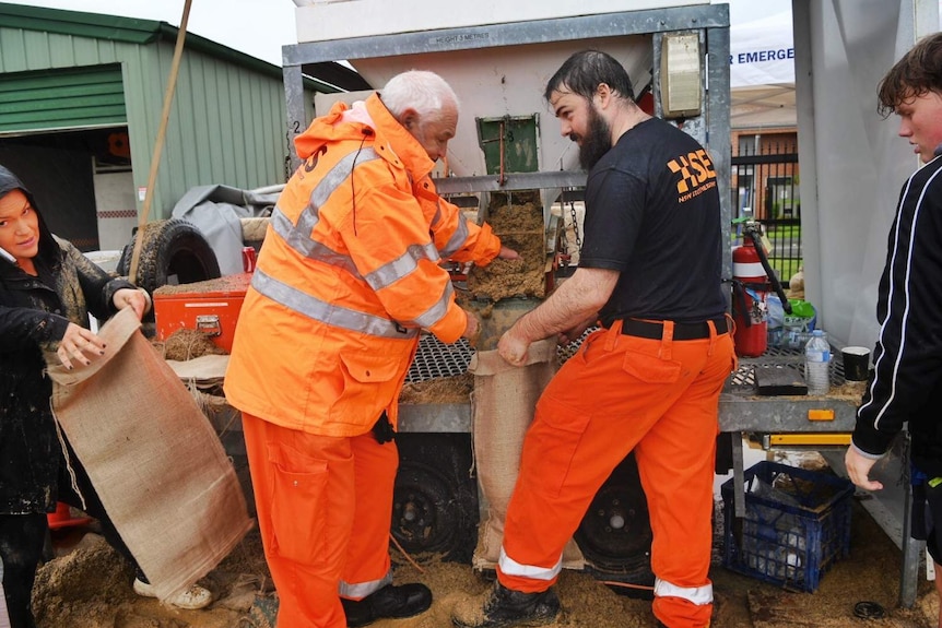 two men holds bags and fill them with sand