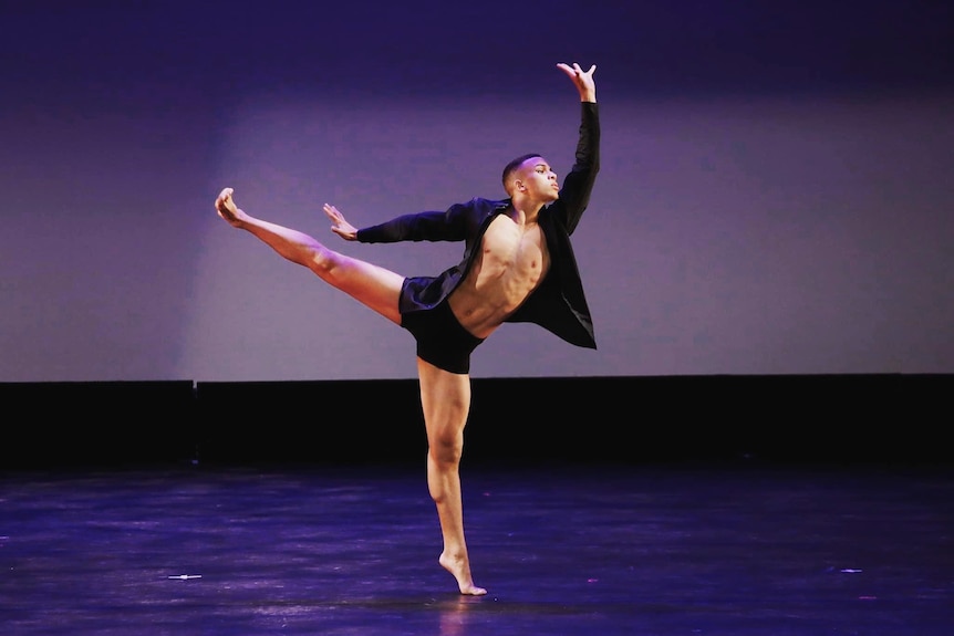 A young man dances on an empty stage 