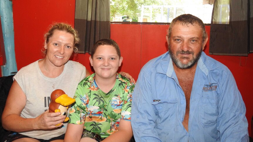 Ryan Jackson with his parents Emma and Neville with the money box they used to remove the snakes from Ryan's arm.