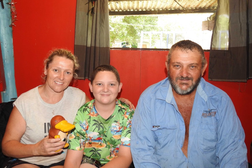 Ryan Jackson with his parents Emma and Neville with the money box they used to remove the snakes from Ryan's arm.