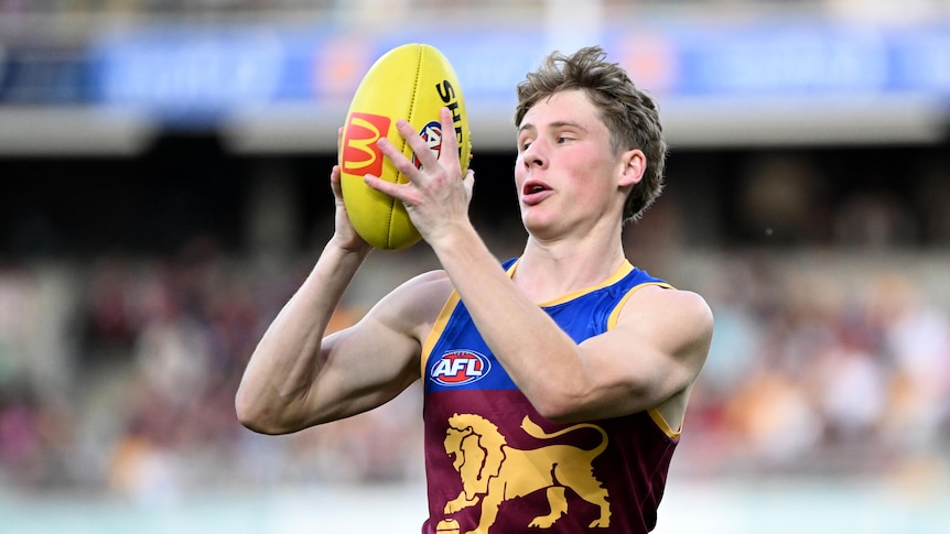 jaspa fletcher holds the ball in front of his face while playing the saints at the gabba