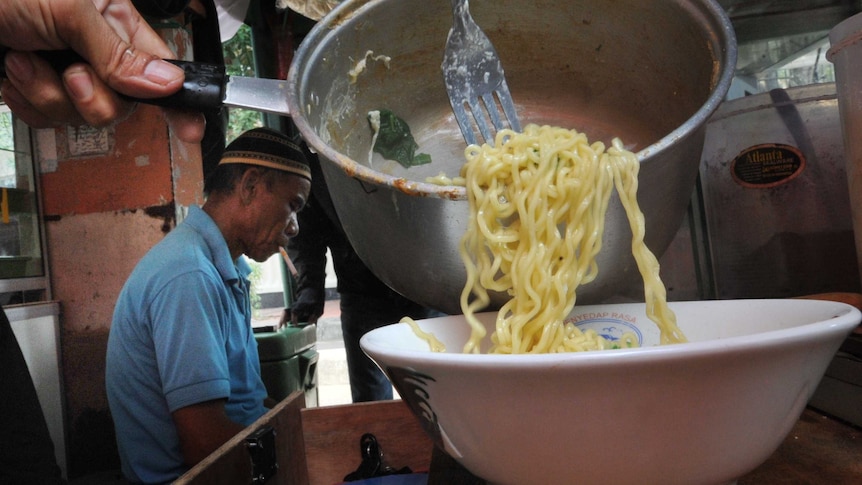 A vendor prepares instant noodles at a stall in Jakarta.