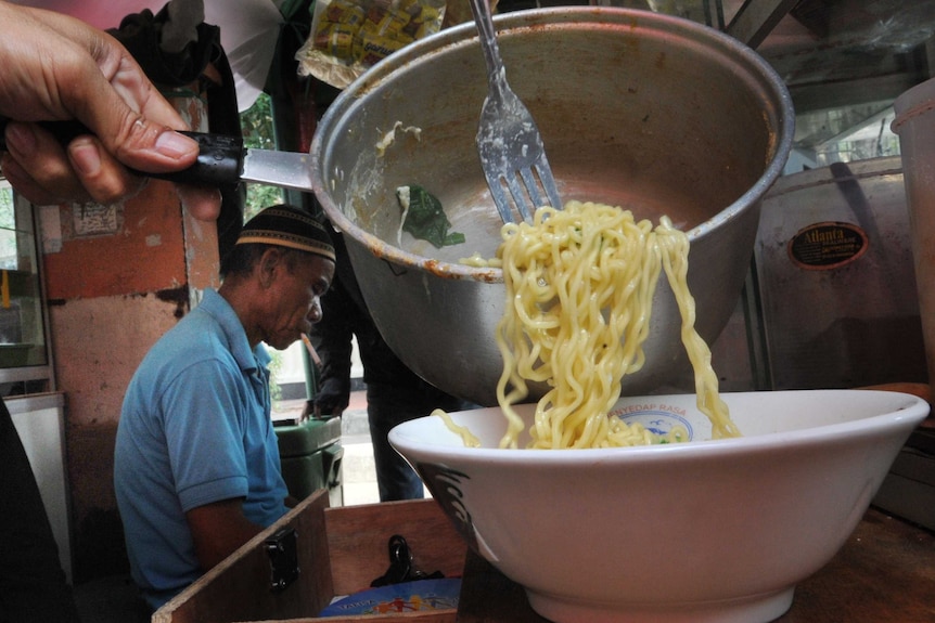 A vendor prepares instant noodles at a stall in Jakarta.