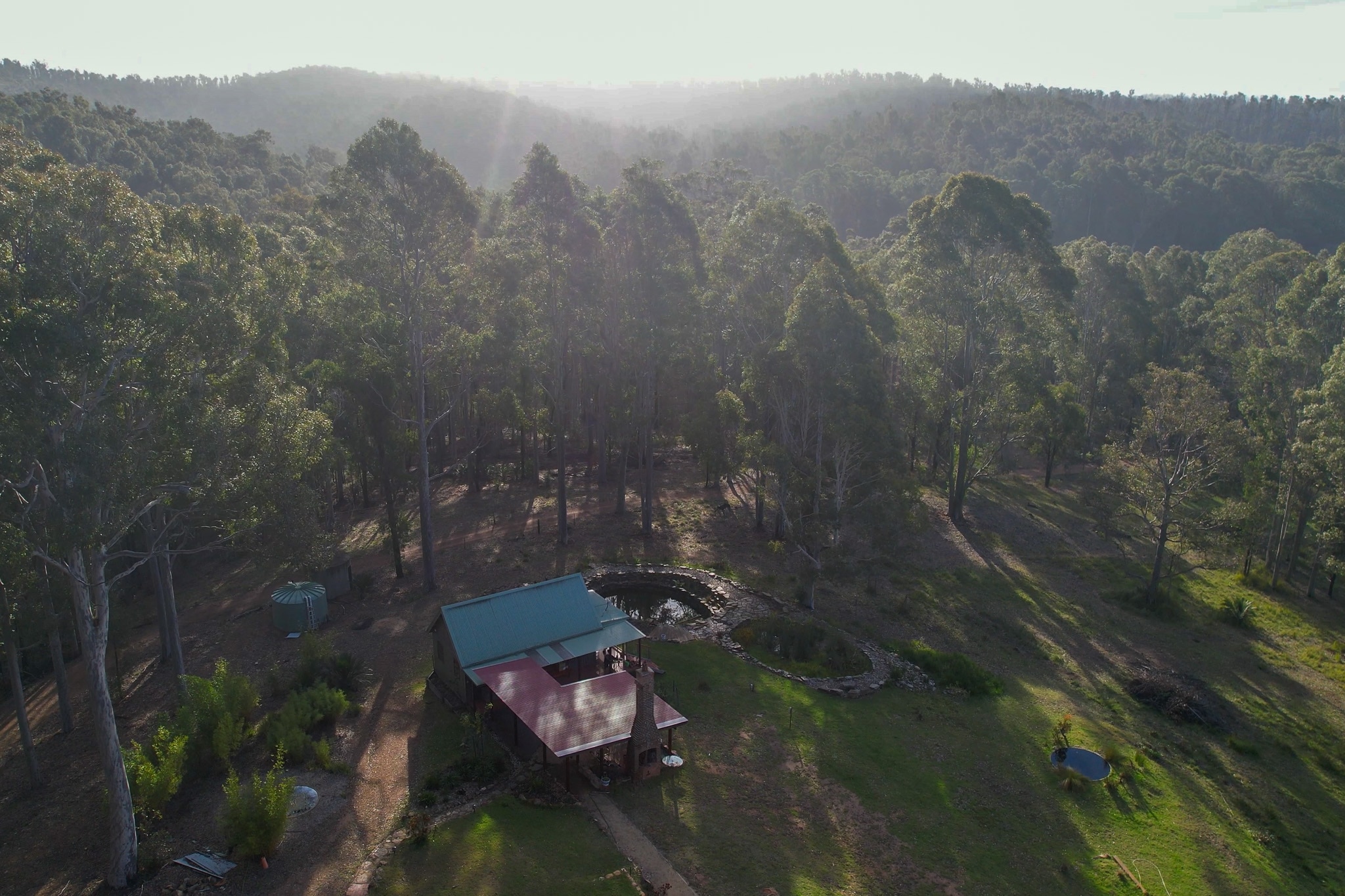 A drone image of small house surrounded by forest.