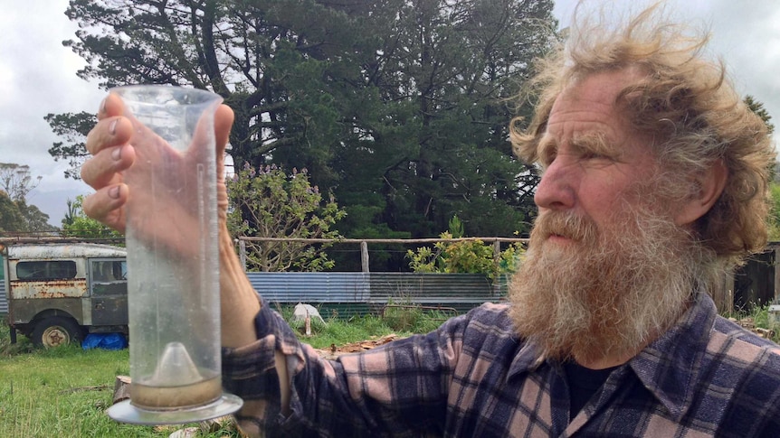 Gray resident Peter Rubenach checks his rain gauge after a heavy dump in north-east Tasmania.