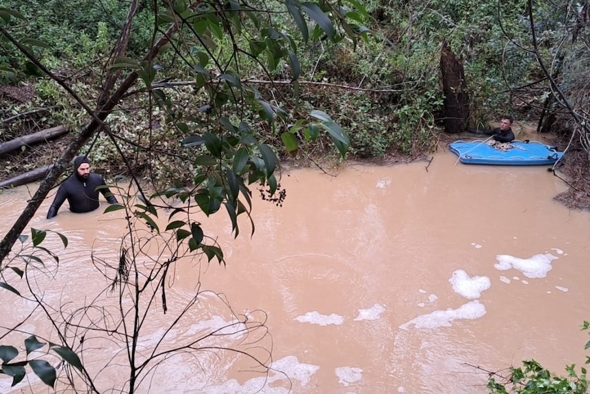 Police divers wade through murky floodwaters