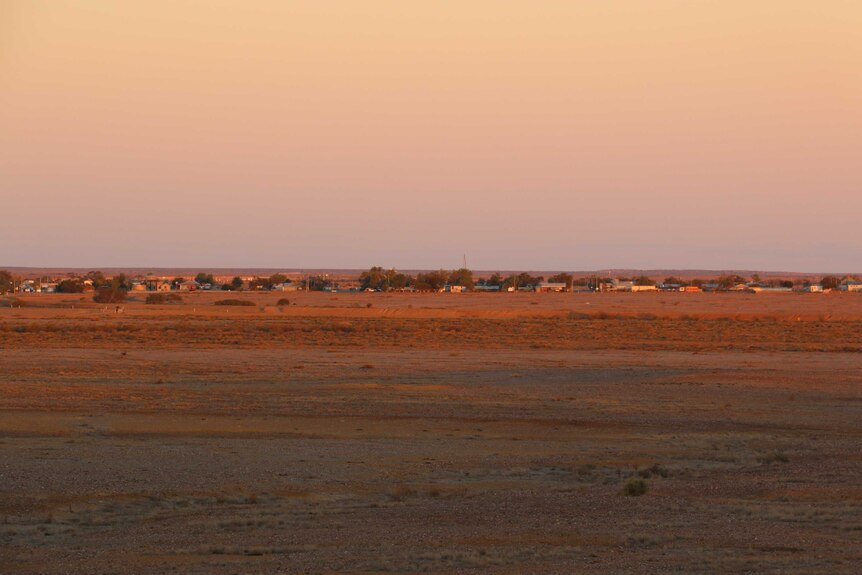 Wide landscape shot of dusk over the outskirts of a small town in the outback.