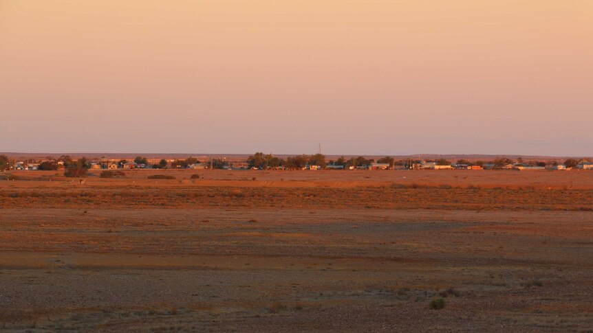 Wide landscape shot of dusk over the outskirts of a small town in the outback.