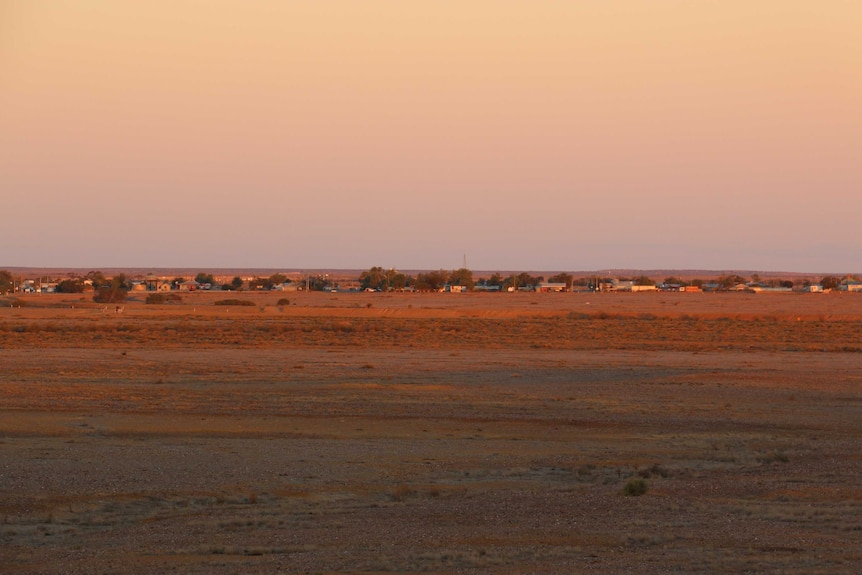 Wide landscape shot of dusk over the outskirts of a small town in the outback.