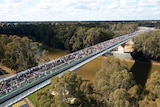 Aerial view of people walking across a bridge.