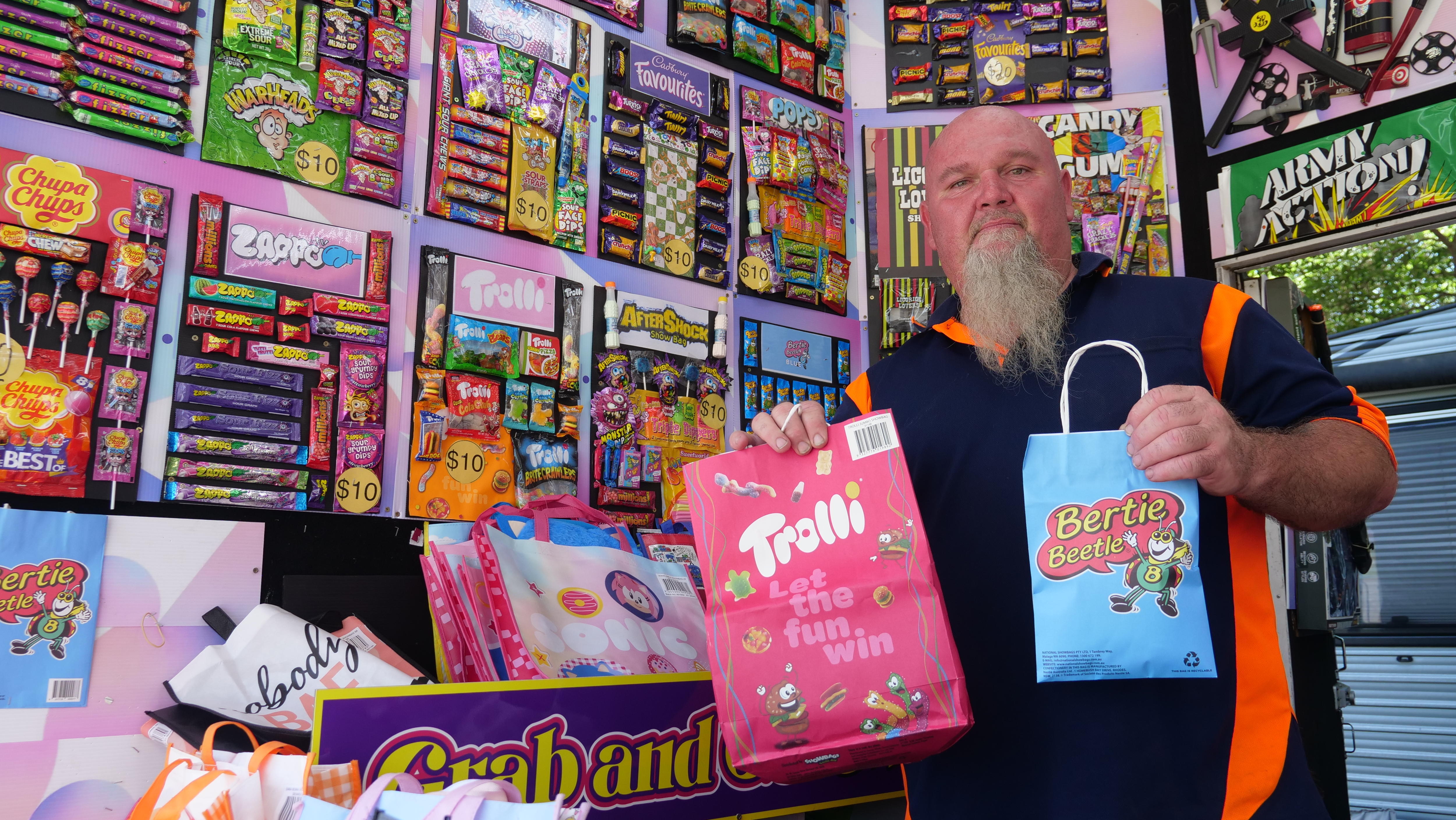 Un hombre está parado en un auto exhibidor rodeado de bolsas de paletas. 