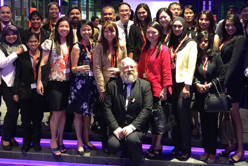 Rick Snell crouches in front of Malaysian students in Kuala Lumpur