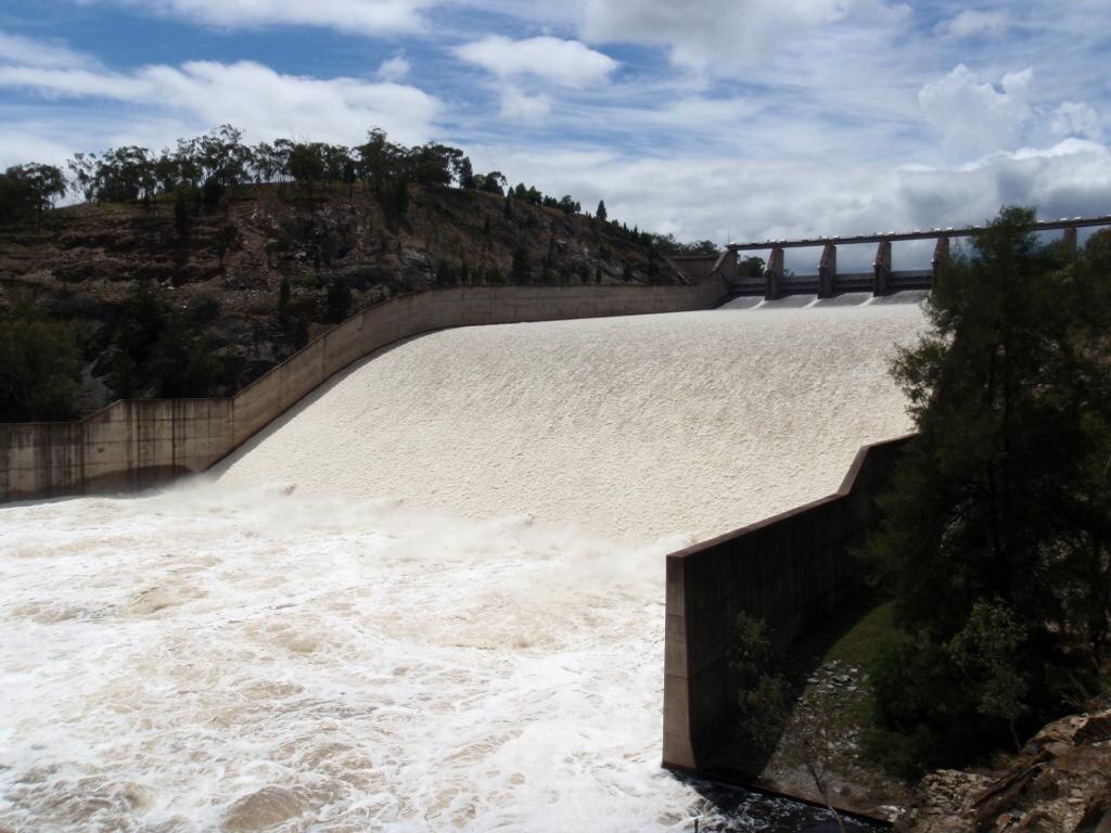 Water pours out of a dam from the top of a spillway down a slope